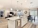 Bright open concept view from kitchen with granite island to living area, dining set, and sliding doors to outdoor patio at 18079 Romanesque Ct, Spring Hill, FL 34610