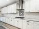 Kitchen featuring white cabinets, granite countertops, subway tile backsplash, and stainless steel range hood at 18079 Romanesque Ct, Spring Hill, FL 34610