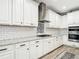 Kitchen featuring white cabinets, granite countertops, subway tile backsplash, stainless steel range hood and appliances at 18079 Romanesque Ct, Spring Hill, FL 34610