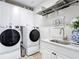 Bright laundry room with white cabinetry, stainless steel appliances, sink and shelving at 18079 Romanesque Ct, Spring Hill, FL 34610