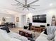 Open-concept living area with a large sectional sofa, entertainment center, and adjacent dining area at 18079 Romanesque Ct, Spring Hill, FL 34610
