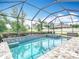 A screened-in pool with attached spa boasts blue tile accents and is surrounded by a brick patio at 18079 Romanesque Ct, Spring Hill, FL 34610
