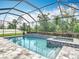 A screened-in pool with attached spa boasts blue tile accents and is surrounded by a brick patio at 18079 Romanesque Ct, Spring Hill, FL 34610
