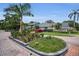 Street view of the community entrance sign, beautifully landscaped with palm trees and flowering plants at 184 Hunter Ct, Palm Harbor, FL 34684