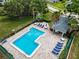 Overhead view of a community pool surrounded by lounge chairs, tables, and meticulously maintained landscaping at 184 Hunter Ct, Palm Harbor, FL 34684