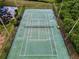 Aerial shot of fenced tennis court with clear markings, set amidst green landscaping and a nearby pond at 184 Hunter Ct, Palm Harbor, FL 34684