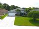 Inviting single-story home with lush green lawn, well-maintained landscaping, and patterned brick driveway at 1842 Ridgelake Ct, Wesley Chapel, FL 33543