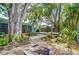 Landscaped backyard with mature trees, a stone firepit area, and a wooden deck, perfect for outdoor enjoyment at 2051 Indigo Dr, Clearwater, FL 33763