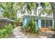 Charming light blue home exterior featuring mature tropical landscaping and a stone pathway to the front door at 2051 Indigo Dr, Clearwater, FL 33763