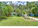 Charming light blue home with a lush green front yard, mature tropical trees and landscaping, and a peacock at 2051 Indigo Dr, Clearwater, FL 33763