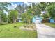 Well-maintained blue home with tropical landscaping, a spacious driveway, and manicured lawn, offering great curb appeal at 2051 Indigo Dr, Clearwater, FL 33763