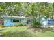 Charming single-story home with light blue exterior, tropical plants, and lush green lawn at 2051 Indigo Dr, Clearwater, FL 33763
