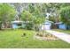 Charming blue home with lush landscaping and a well-manicured lawn, set among mature trees, creating a tranquil oasis at 2051 Indigo Dr, Clearwater, FL 33763