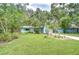 Landscaped front yard with a charming blue house, surrounded by lush trees and well-maintained greenery at 2051 Indigo Dr, Clearwater, FL 33763