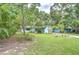 Picturesque front yard with a vibrant lawn and mature trees surrounding a cozy blue home, creating a peaceful setting at 2051 Indigo Dr, Clearwater, FL 33763