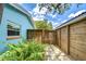 Stone pathway lined with plants leads to a wooden gate in a serene and private landscaped side yard at 2051 Indigo Dr, Clearwater, FL 33763