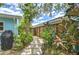 Landscaped side yard with a stone pathway, wooden fence, and a variety of mature tropical plants and foliage at 2051 Indigo Dr, Clearwater, FL 33763