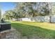 Wide shot of backyard with well-kept grass, tall trees, and a tall gray privacy fence at 2248 Lake Woodberry Cir, Brandon, FL 33510