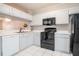 Bright kitchen features white cabinets, black appliances, and white tile flooring at 2316 Lake Woodberry Cir, Brandon, FL 33510