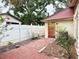 Backyard with decorative brick pathway leads to home entrance; white fence in view at 2523 Krueger Lane, Tampa, FL 33618