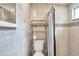 Bathroom with a toilet and updated shower with neutral tiling and silver metal shelving at 2808 N Highland Ave, Tampa, FL 33602