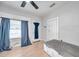 Bedroom featuring light wood-look flooring, window with curtains, ceiling fan, and two doors at 2808 N Highland Ave, Tampa, FL 33602