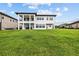 Large green backyard featuring the home's back facade, with a covered balcony at 28565 Picana Ln, Wesley Chapel, FL 33543