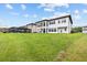 Spacious backyard with green lawn and a modern house featuring a covered patio and plenty of windows at 28565 Picana Ln, Wesley Chapel, FL 33543