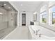 Bright bathroom with tiled floors, soaking tub and glass enclosed shower at 28565 Picana Ln, Wesley Chapel, FL 33543