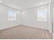 Bright, neutral bedroom featuring two windows, plush carpeting and a doorway with white trim at 28565 Picana Ln, Wesley Chapel, FL 33543