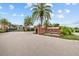 A community entrance sign surrounded by lush landscaping and mature palm trees at 28565 Picana Ln, Wesley Chapel, FL 33543