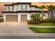 Elegant two-story home showcasing a tile roof, two-car garage, and lush tropical landscaping at 28565 Picana Ln, Wesley Chapel, FL 33543