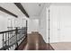 Hallway featuring hardwood floors, beam details and a wrought iron stair railing at 28565 Picana Ln, Wesley Chapel, FL 33543
