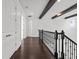 Hallway with hardwood floors, black railings, and beams that adds a modern yet cozy touch to the interior at 28565 Picana Ln, Wesley Chapel, FL 33543