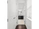 Hallway with dark hardwood flooring leading to bathroom with dual vanity and tile flooring at 28565 Picana Ln, Wesley Chapel, FL 33543