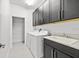 Well-equipped laundry room features modern washer, dryer, sink, and ample cabinet storage space at 28565 Picana Ln, Wesley Chapel, FL 33543