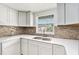 Close up of kitchen featuring white cabinets, modern sink, and stylish backsplash at 3008 E Wilder Ave, Tampa, FL 33610