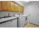 Functional laundry room with overhead cabinets, utility sink, modern washer and dryer, and tile flooring at 3089 Ashland Ter, Clearwater, FL 33761