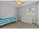 Bright bedroom with a twin bed, dresser, ceiling fan, and natural light from the window at 3138 Deergrass Ct, Holiday, FL 34691