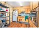Retro kitchen featuring wood cabinets, matching backsplash, modern stainless steel oven, storage shelves, and hardwood floors at 3201 E Mcberry St, Tampa, FL 33610