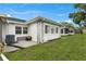 Exterior view with green backyard, stone accents, utility access and well-maintained lawn at 3271 Mcmath Dr, Palm Harbor, FL 34684