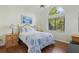 Bright bedroom with a quilt-covered bed, hardwood floors, and a large window for natural light at 3457 Foxhall Dr, Holiday, FL 34691