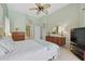 Bright bedroom with light green walls, dresser, TV and connecting bathroom at 3457 Foxhall Dr, Holiday, FL 34691