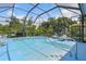 Wide shot of screened in pool area, featuring lounge chairs, a table and clear water at 3457 Foxhall Dr, Holiday, FL 34691