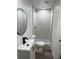 Bathroom with white vanity, round mirror, and glass-enclosed shower with marble-look tile at 3844 Cedarwood Dr, Holiday, FL 34691
