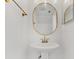 Small powder room features a pedestal sink with gold fixtures and a stylish mirror at 409 S Audubon Ave # 3, Tampa, FL 33609
