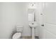 A well-lit half bathroom featuring a pedestal sink, a toilet, and a large mirror above the sink at 4206 W North B St # 1, Tampa, FL 33609