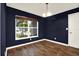 Bedroom with dark blue walls, hardwood floors, large window and white trim at 4342 Candler Ave, Spring Hill, FL 34609