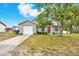 Charming gray home with a well-manicured lawn, mature trees, and a welcoming red front door at 4342 Candler Ave, Spring Hill, FL 34609