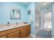 A blue bathroom includes tile flooring, wood cabinets, a shower, and a separate door to the pool at 460 Meravan Dr, Palm Harbor, FL 34683